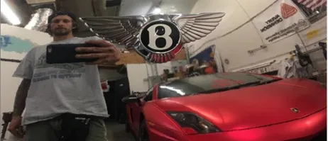 Installer beside a satin red Lamborghini Gallardo in the shop